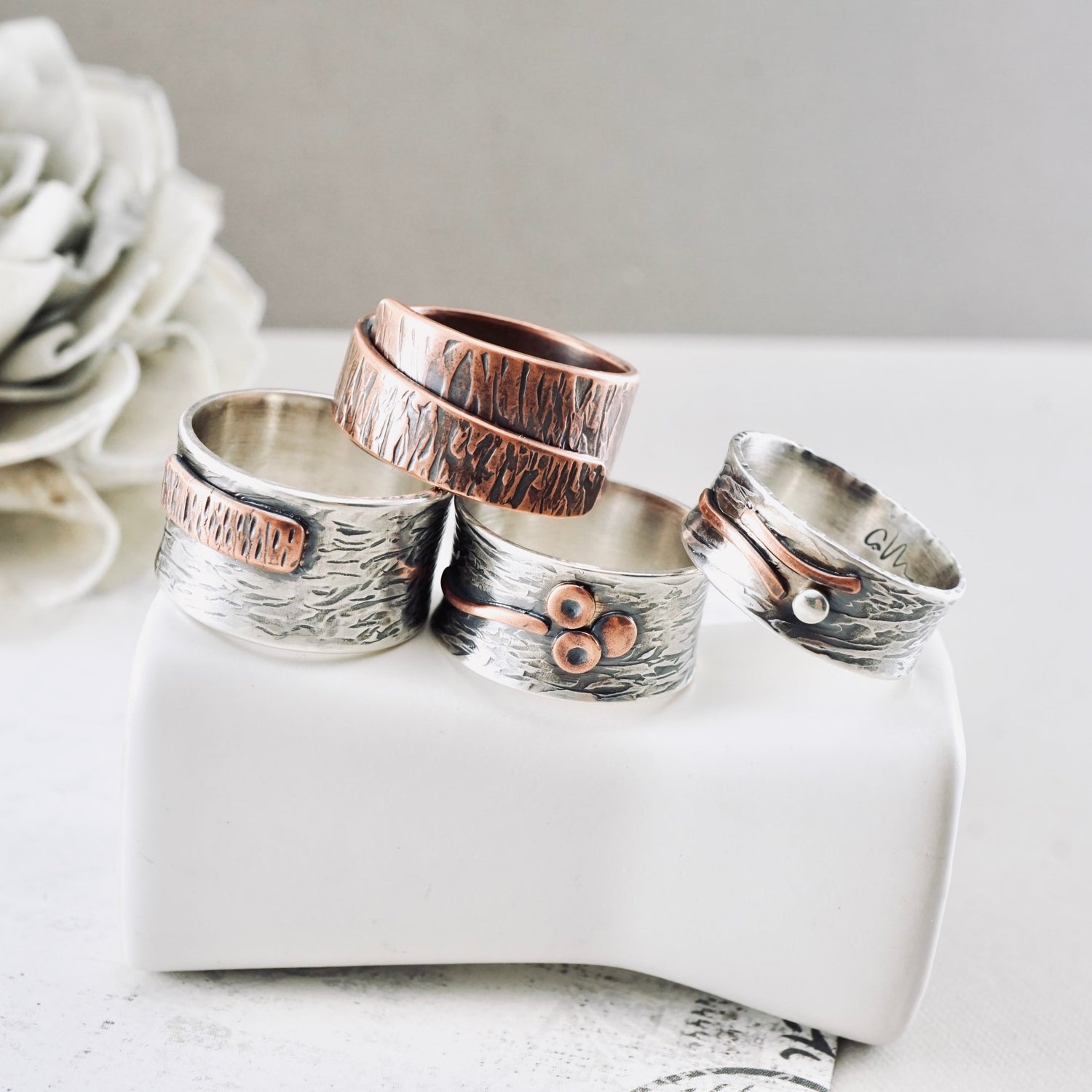 Four handcrafted rings in sterling silver on a wooden pole